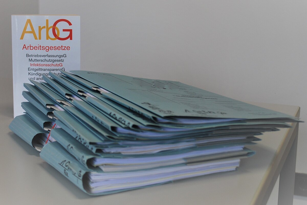 [Bild] Tisch mit Aktenstapel und Gesetzbuch Arbeitsgesetze