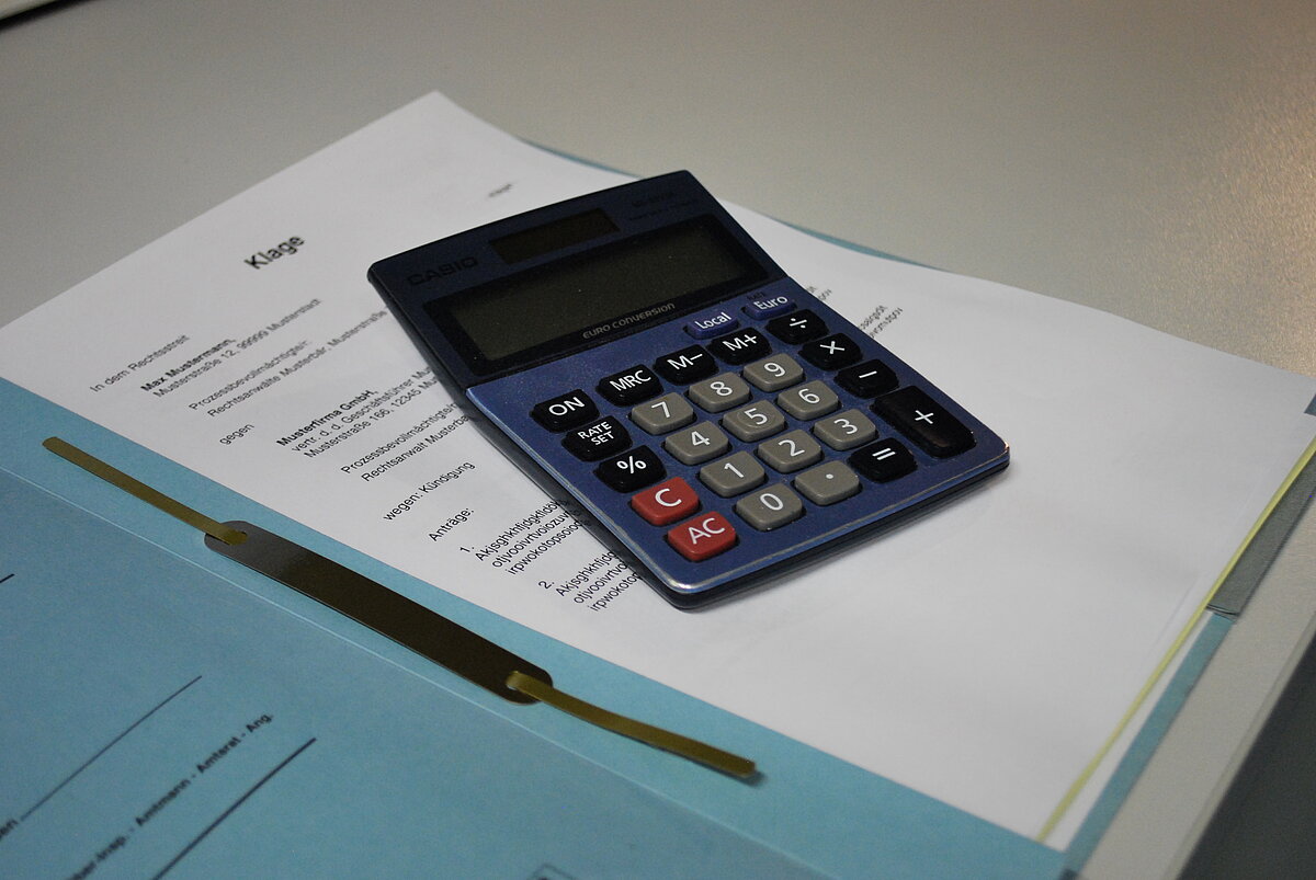 [Bild] Taschenrechner auf einer aufgeschlagenen Akte